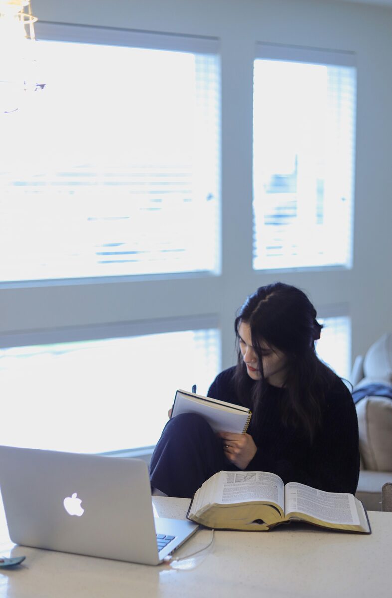A student studying with her notebook and laptop