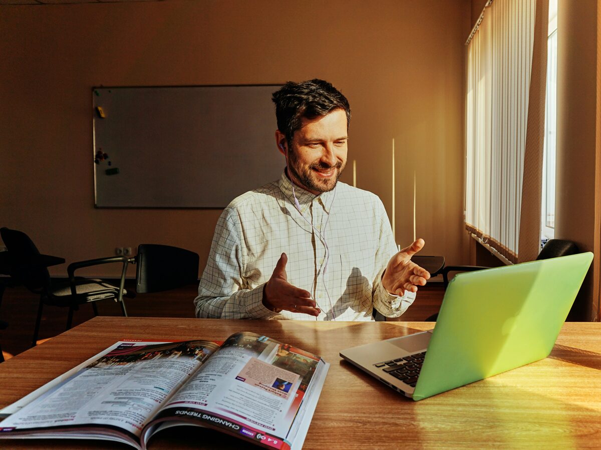 A smiling tutor explaining something at a desk
